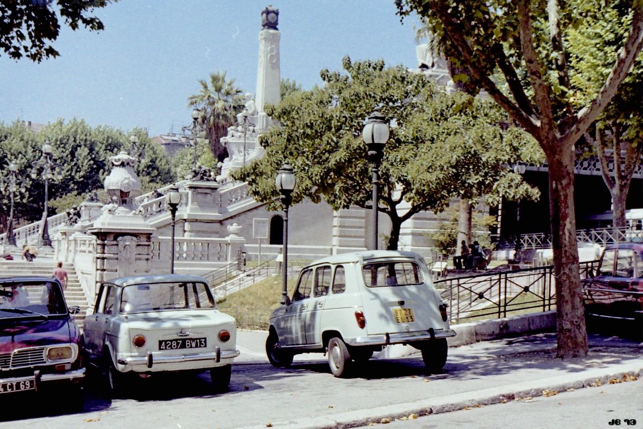 Verblasstes Farbfoto, aufgenommen 1973 in Marseille, Frankreich. Vor einem Monument mit Treppe und Obelisk sind drei zeitgenössische Autos geparkt.